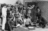 Children cementing their tiles to a wall. 1970